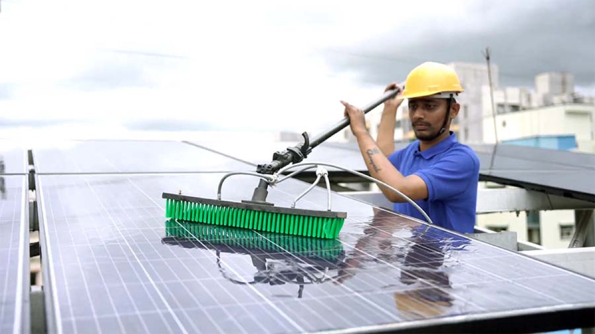 Technician cleaning rooftop solar panels
